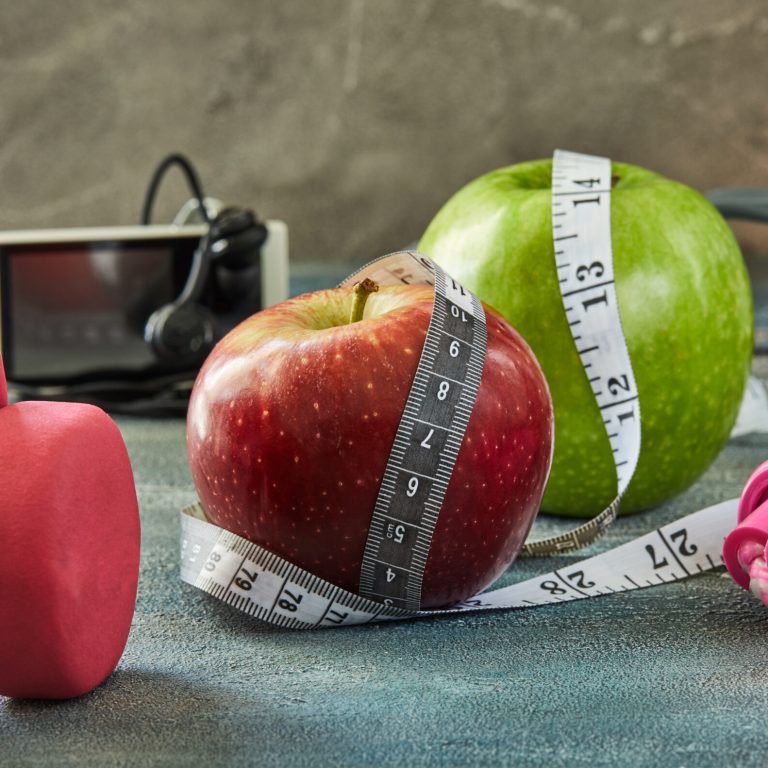 Attributes of a healthy lifestyle. Fruits, dumbbells, a bottle of water, rope, meter, player on a blue background with stains. Diet plan. Side view. Sport and healthy mode.